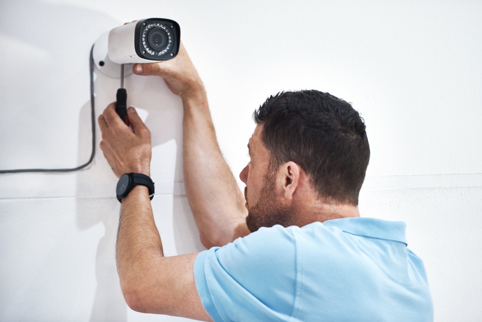 Shot of a mature man installing a security camera on a building
